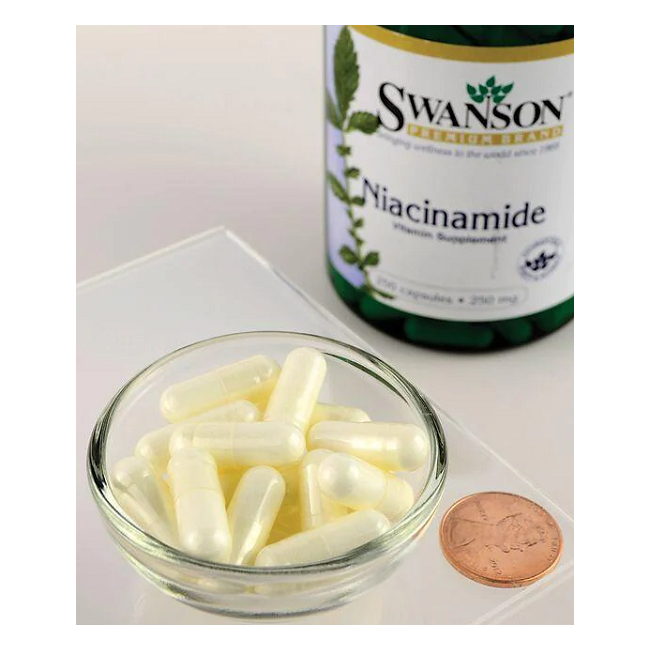 A bowl of white capsules sits next to a penny and a bottle labeled "Swanson," emphasizing the essential role of Swanson Niacinamide (Vitamin B3) 250 mg 250 Capsules as a dietary supplement.