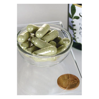 Thumbnail for A small glass bowl holds green capsules full of antioxidants, with a penny for scale. In the background, a partially visible bottle featuring a leaf design indicates Swanson's Full Spectrum Moringa Oleifera 400 mg capsules, known for their beneficial phytonutrients.