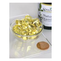 Thumbnail for A small glass bowl with several yellow softgels of Swanson Natural Vitamin E-400 IU, enriched with tocopherols, sits next to a coin and a vitamin bottle.