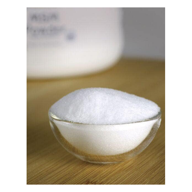 A small glass bowl filled with organic sulfur compound MSM powder from Swanson sits on a wooden surface, promoting joint health. In the background, a blurred white container of Swanson MSM Powder - Ready-Mix & Unflavored 454 grams is visible.