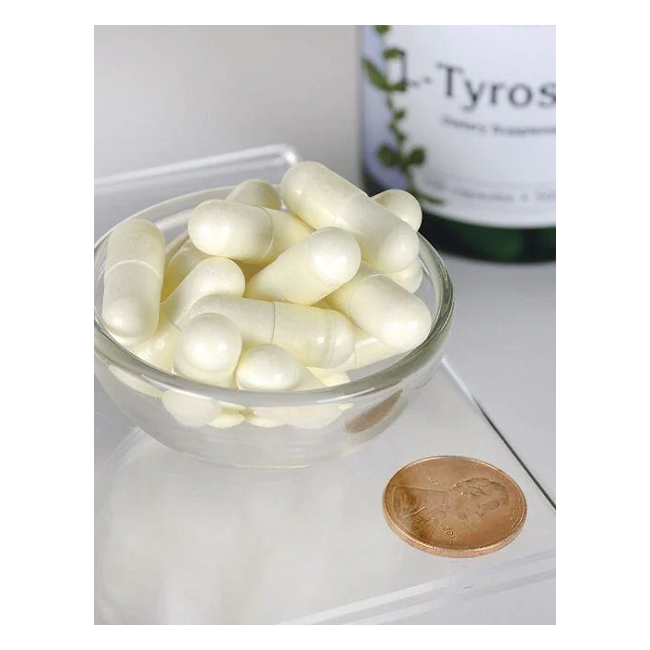 A small glass bowl holds white capsules, likely L-Tyrosine, a dopamine-enhancing amino acid, next to a penny for scale. In the background, a Swanson bottle labeled "L-Tyrosine 500 mg 100 Capsules" is partially visible.