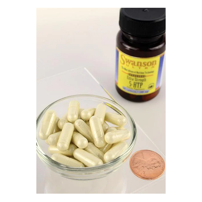 A glass bowl of white capsules sits beside a bottle labeled "Swanson 5-HTP (Hydroxytryptophan) 100 mg," derived from Griffonia simplicifolia, with a penny nearby for size comparison.