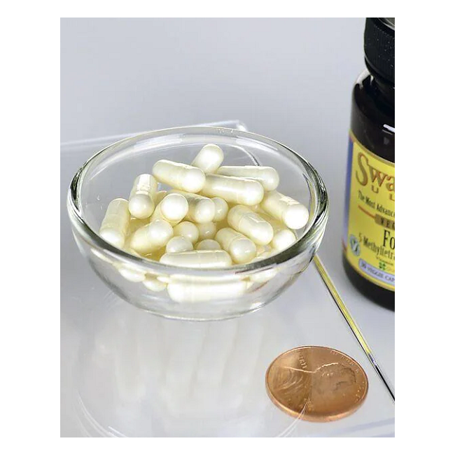 A small glass bowl with white capsules is next to a penny for scale and a Swanson bottle labeled "Folate 5-MTHF - 800 mcg 30 capsules" featuring advanced Quatrefolic technology.