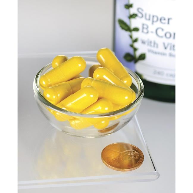 Swanson Capsule di B-Complex con vitamina C in una ciotola accanto a un penny.