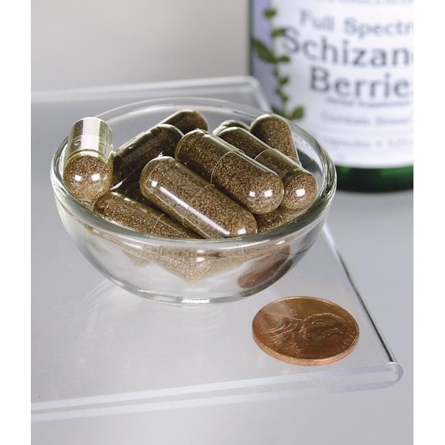 SwansonLe bacche di Schizandra - 525 mg 90 capsule, un tonico per il fegato e un adattogeno, sono esposte in una ciotola accanto a un penny.