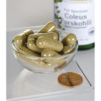 Miniatura di Swanson Coleus Forskohlii - 400 mg 60 capsule in una ciotola accanto a un centesimo.