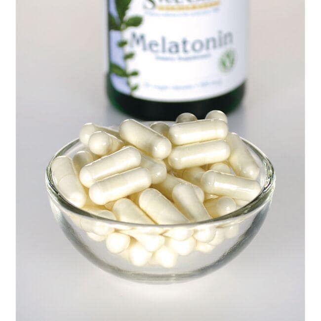 Swanson Melatonina - 0,5 mg 60 capsule vegetali in una ciotola di vetro accanto a una bottiglia.