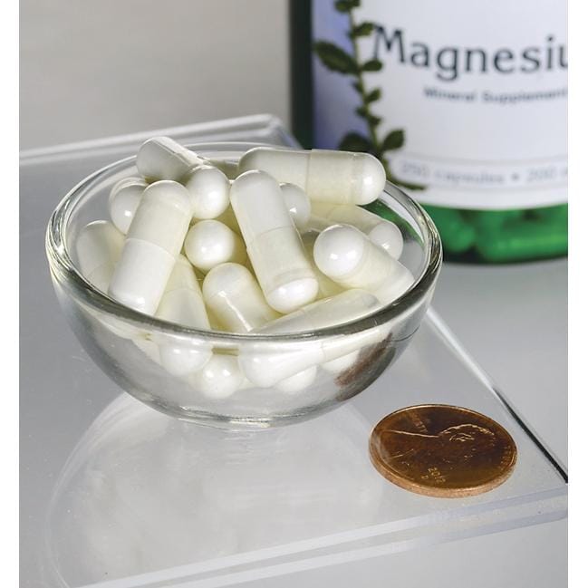Una ciotola di pillole bianche accanto a un flacone di Swanson Magnesium Oxide - 200 mg 250 capsule.