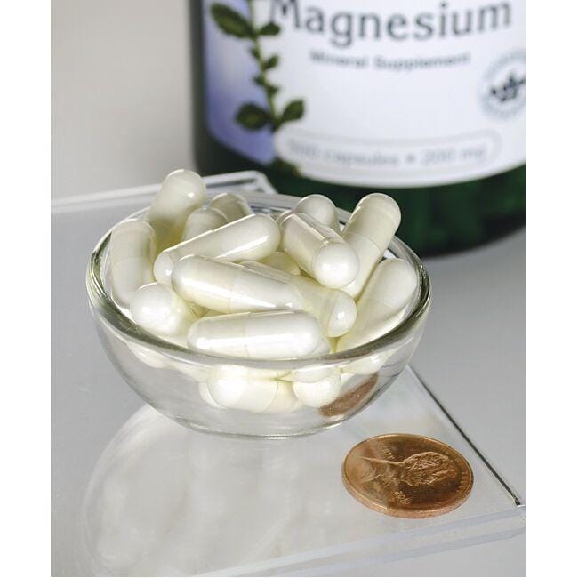 Swanson Ossido di magnesio - 200 mg 500 capsule in una ciotola accanto a una bottiglia.