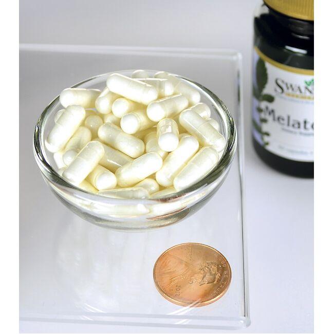 Una ciotola di Swanson Melatonina 3 mg 60 capsule accanto a un centesimo.