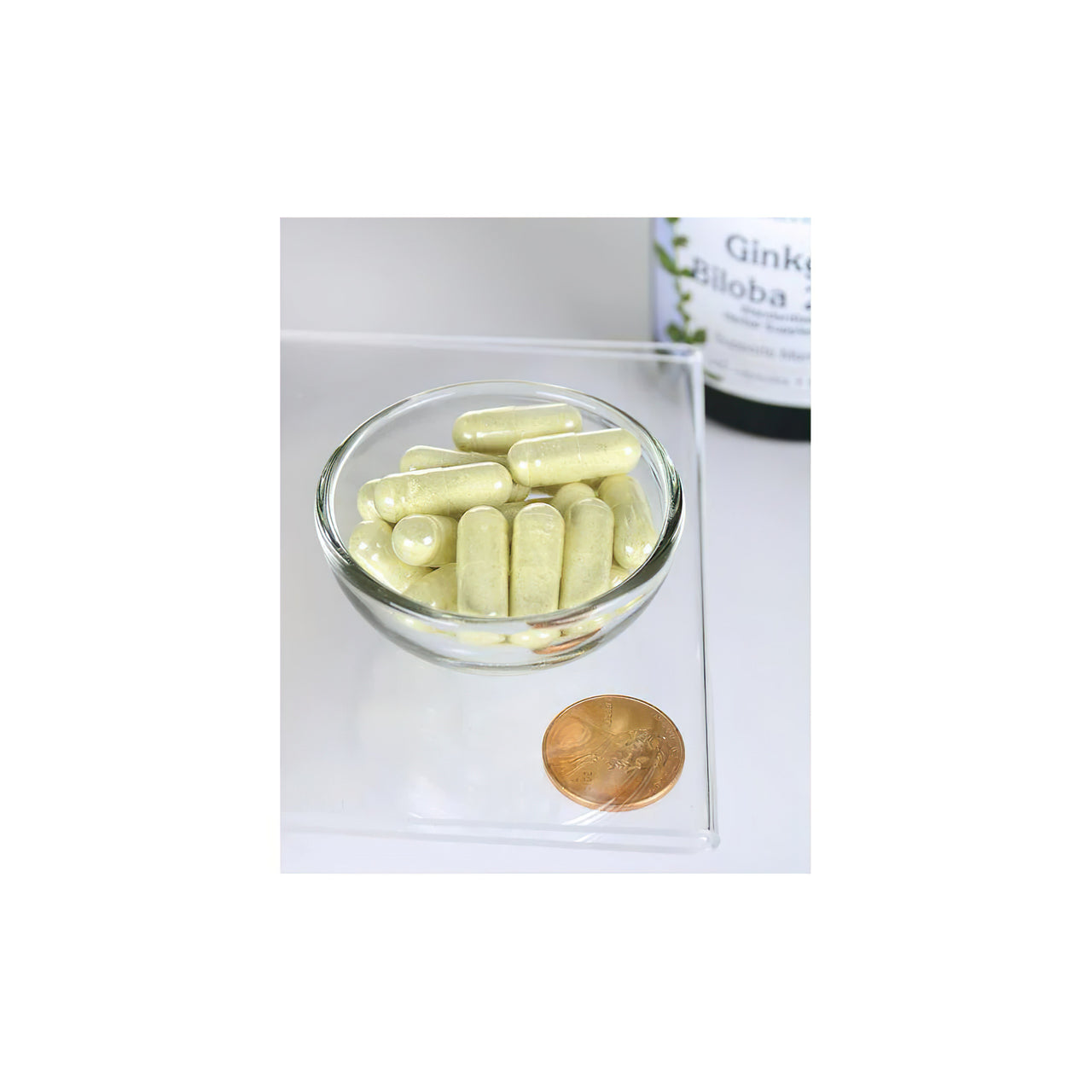 Una ciotola di Swanson Ginkgo Biloba Extract 24% 60 mg 240 cap con una moneta accanto.