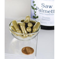 Miniatura di Swanson Saw Palmetto - 540 mg 250 capsule, note per il loro ruolo nel promuovere la salute della prostata e il flusso del tratto urinario, sono esposte in una ciotola accanto a un penny.