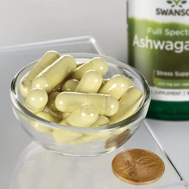 Una ciotola di Swanson Ashwagandha - 450 mg 100 capsule con accanto una moneta.
