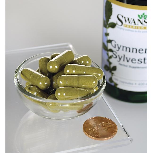 Un flacone di Swanson Gymnema Sylvestre Leaf - 400 mg 100 capsule con una monetina in una ciotola.