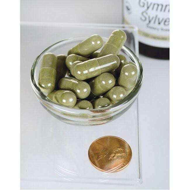 Una ciotola di Swanson Gymnema Sylvestre Extract - 300 mg 120 capsule accanto a una moneta.