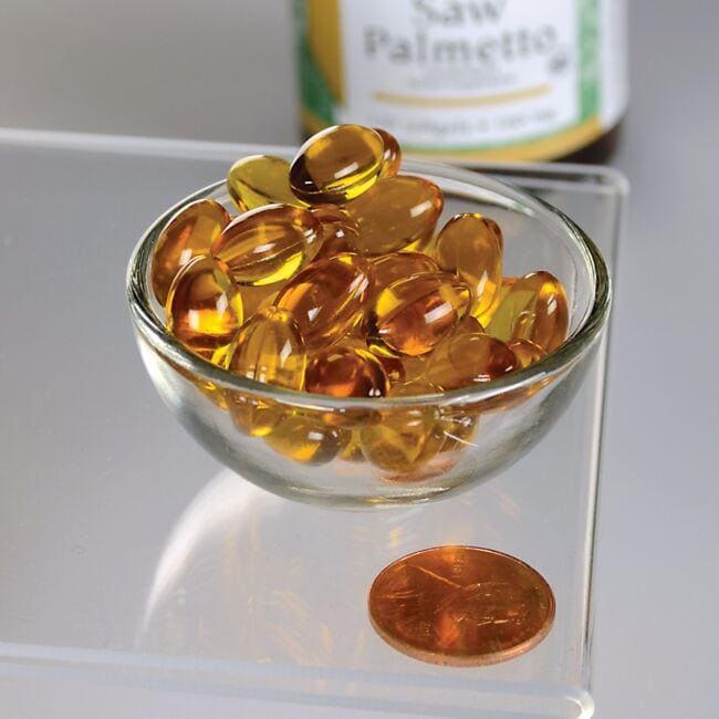 Una ciotola di Swanson Saw Palmetto - 160 mg 120 softgel accanto a un centesimo, per promuovere la salute della prostata.