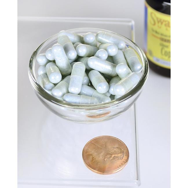 Una ciotola di Swanson Rame - 2 mg 60 capsule Albion Chelated accanto a un centesimo.