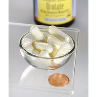 Miniatura di Magnesio Orotato - 40 mg 60 capsule da Swanson in una ciotola di vetro accanto a un centesimo.