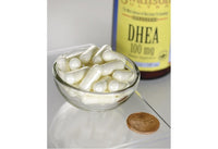Miniatura di Swanson DHEA - 100 mg 60 capsule in una ciotola accanto a un penny.
